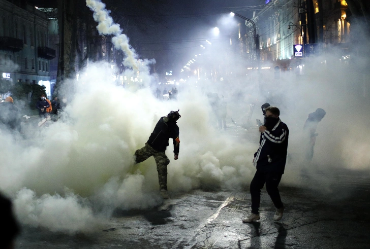 Протестующий отбрасывает баллончик со слезоточивым газом во время акции протеста в Тбилиси, Грузия, 8 марта 2023 года | maximonline.ru