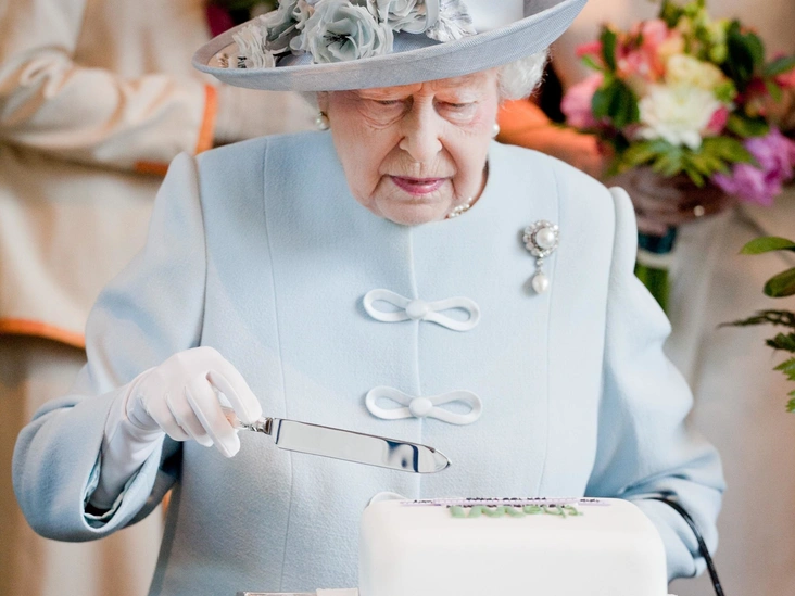 Елизавета II разрезает торт на ежегодном съезде общественной организации The National Federation Of Women's Institutes, Лондон, 4 июня 2015