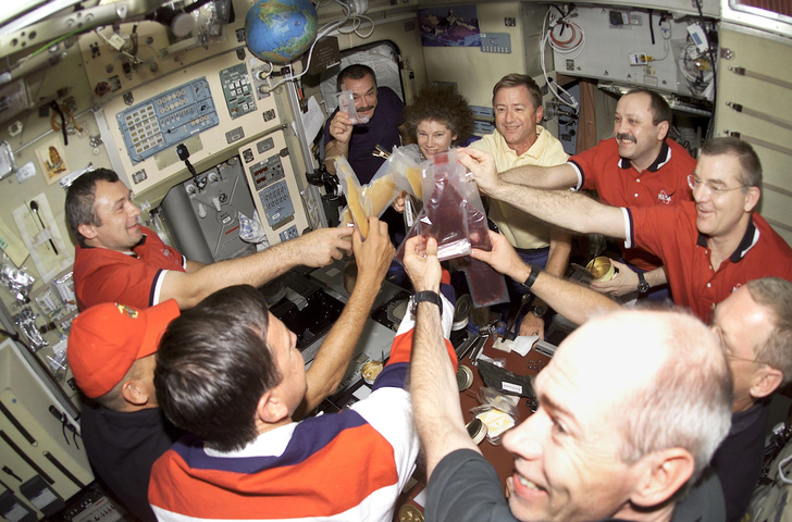 Астронавты и космонавты второй и третьей экспедиции на МКС поднимают целлофановые пакеты в честь присоединения к станции нового модуля, «Звезда». Конечно, в пакетах у них соки. Но почему лица так оживлены? 15 августа 2001 г.