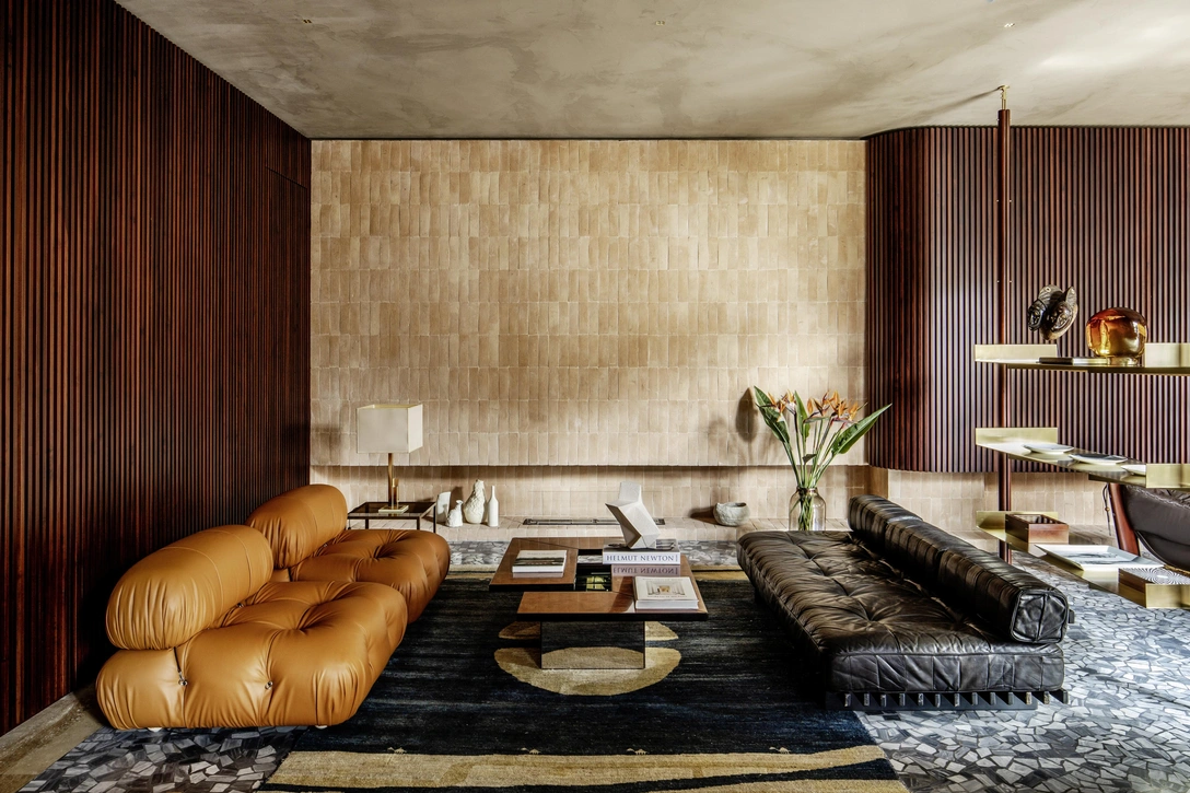 Вокруг винтажного кофейного стола по дизайну Вилли Риццо, 1972, — винтажный диван, Швейцария, 1980-е, и диван Camaleonda, B&B Italia (слева). Скульптуры из керамики, Ceramiche Milesi. Открытый стеллаж выполнен по дизайну Ханнеса Пира. На стеллаже: африканская скульптура, Конго, конец XIX века; скульптура Ego из муранского стекла Урсулы Хубер; посуда, Fornasetti. Стены декорированы деревянными панелями буазери по дизайну Ханнеса Пира. Стена за камином, Altrofuoco, облицована изготовленным вручную кирпичом, Fornace Bernasconi. На полу — винтажный персидский ковер. | Источник: Эленио Барбетта