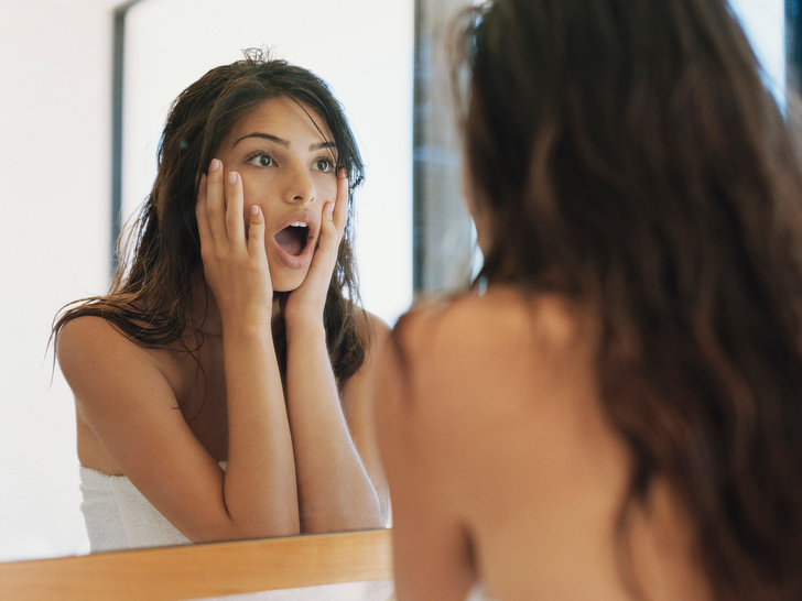 Красивая женщина делает макияж перед зеркалом в ванной