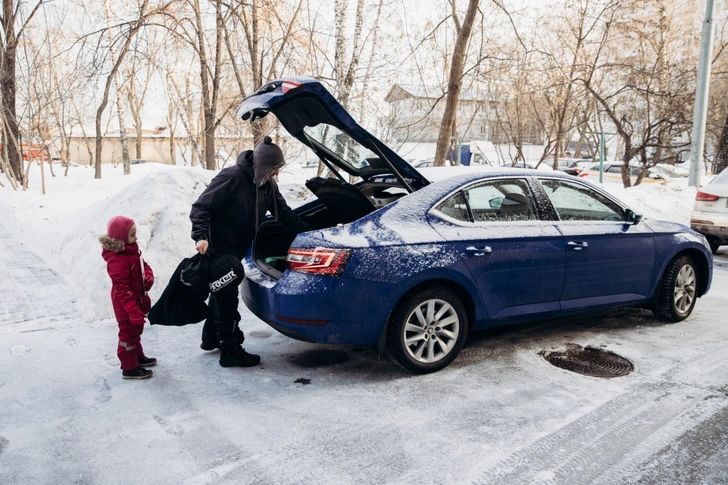 Папа и дочка загружают спортивную экипировку в багажник автомобиля ŠKODA Superb