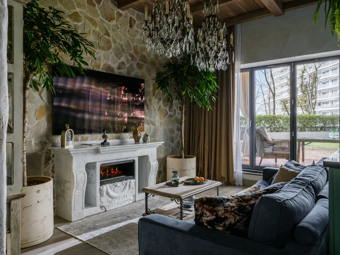 Кухня-гостиная. Потолок выполнен на заказ из массива дуба, Arttex Home. Камин изготовлен на заказ из натурального мрамора по эскизам дизайнера, «Мастерская камня Артема Синицина». На камине — скульптура Андрея Осташева. Паркет, L`antic Colonial. Люстры, Eichholtz. | Источник: Михаил Чекалов