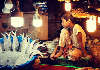 Юный продавец присматривает за товаром на рынке в Дакке